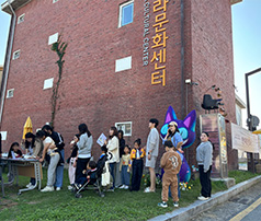 나주나비문화센터 벽면 아래 잔디밭에서 가족 단위 방문객들이 줄을 서서 행사 안내를 받거나 참여를 기다리는 모습