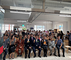 실내 행사장에 모인 수십 명의 참여자가 정면을 향해 주먹을 쥐고 파이팅 포즈를 취하며 단체 기념사진을 촬영하는 모습