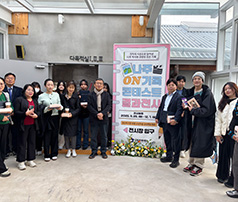 '나주 ON 가족 콘테스트 결과전시' 홍보물 앞에서 행사 관계자들과 참여자들이 전시관 입구에 모여 기념사진을 찍는 모습