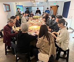 아늑한 실내 공간에서 참여자들이 긴 테이블에 둘러앉아 꽃과 식물을 활용한 원예 활동이나 수공예 체험에 집중하고 있는 모습