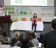 '생명과 공동체, 그리고 예술'이라는 주제의 나주문화센터 프로그램에서 분홍색 재킷을 입은 강사가 마이크를 들고 청중 앞에서 강연을 진행하는 모습